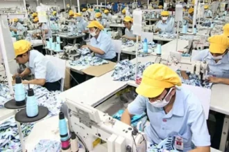 Para pekerja sedang menjahit di sebuah pabrik garmen