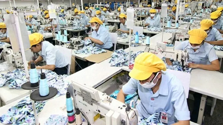 Para pekerja sedang menjahit di sebuah pabrik garmen